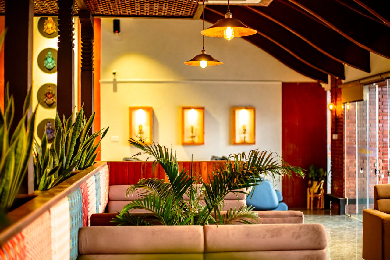 A warm and inviting modern cafe interior featuring plants, cozy seating, and ambient lighting.