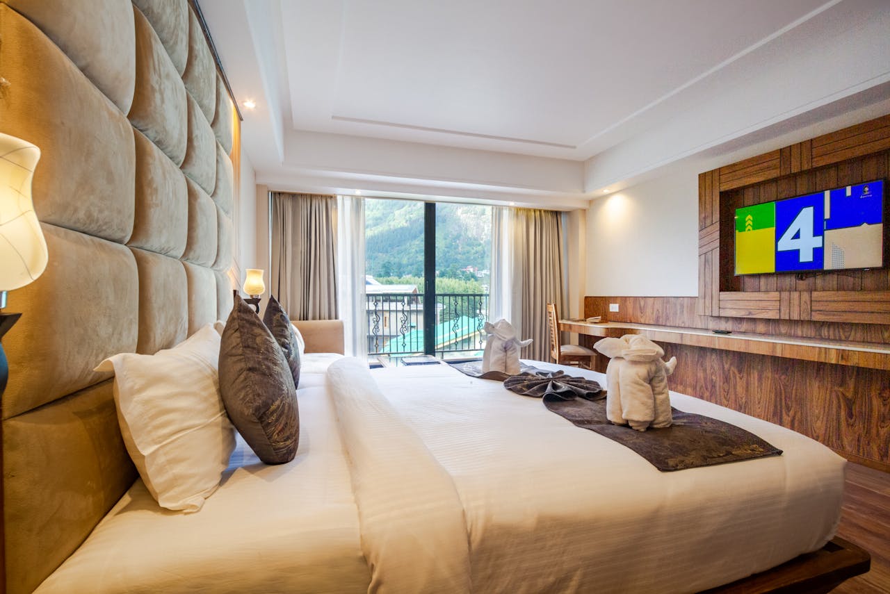 Elegant hotel room with a large bed and scenic mountain view from the window, ideal for a comfortable stay.